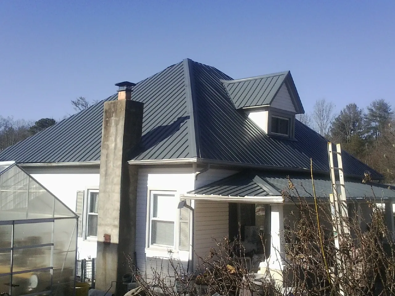 Dark blue standing seam metal roof on a white farmhouse with dormer — Slate & Tile Roof Repair by Roofing Brothers in Augusta