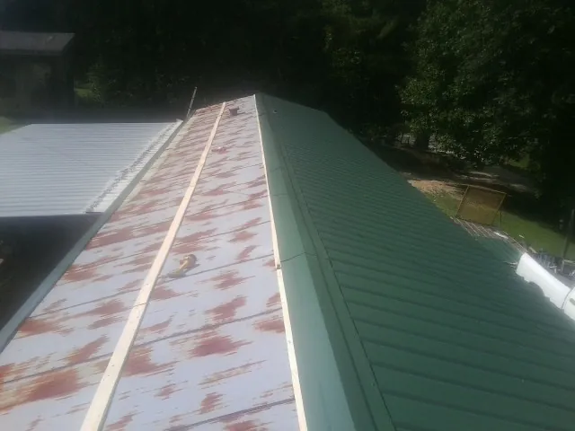 Old rusted panels beside newly installed green metal roofing — Wind Damage Roof Repair by Roofing Brothers in Augusta
