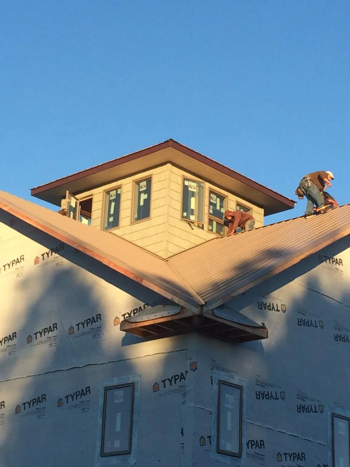 Roofers working around a rooftop cupola on a new metal roof at sunset — Roof Waterproofing in Augusta by Roofing Brothers